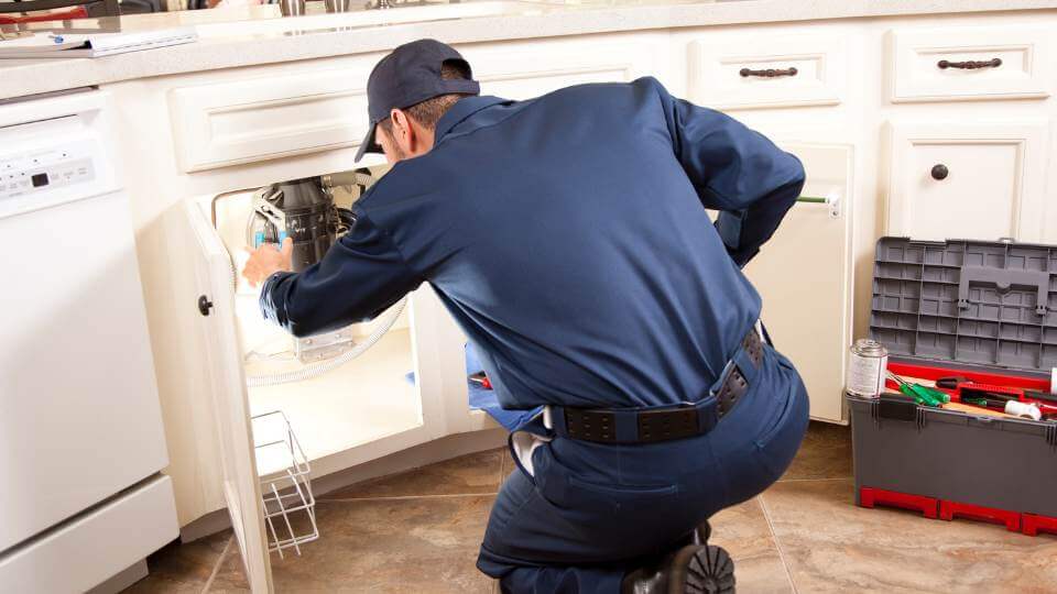 Plumber looking under the sink