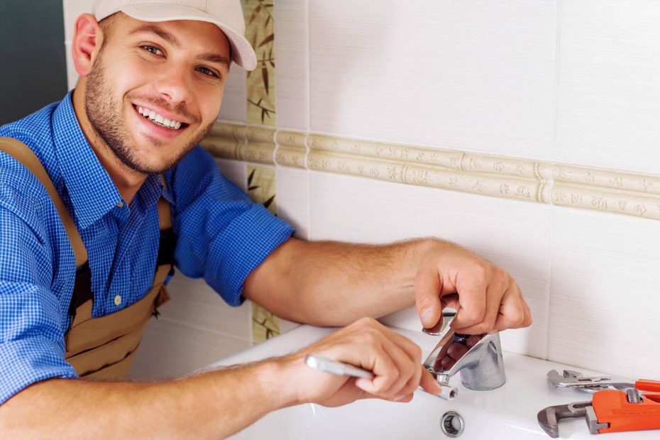 Smiling plumber fixing a sink